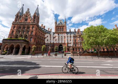 Un solo ciclista passa davanti al St Pancras Hotel durante il Covid 19 Lockdown, Londra. Foto Stock