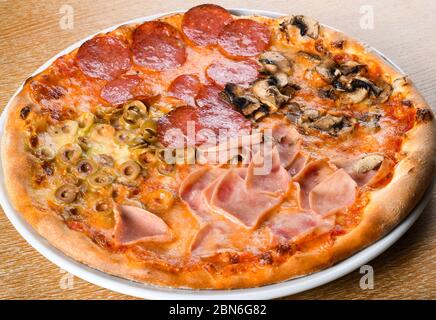La pizza quattro stagioni è una varietà di pizza della cucina italiana che viene preparata in quattro sezioni con ingredienti diversi, con ogni sezione repressen Foto Stock