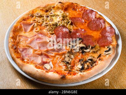 La pizza quattro stagioni è una varietà di pizza della cucina italiana che viene preparata in quattro sezioni con ingredienti diversi, con ogni sezione repressen Foto Stock