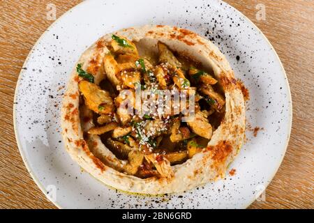 L'hummus è un piatto di salsa, spalmato o salato a base di ceci cotti, schiacciati, mescolati con tahini, succo di limone e aglio. È popolare nel Medio E. Foto Stock