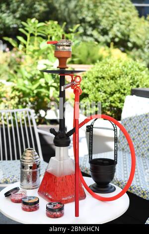 Hokah shisha sul tavolo del ristorante nel giardino. Gancio metallico su una terrazza estiva con sfondo sfocato. Foto Stock