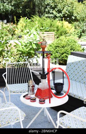 Hokah shisha sul tavolo del ristorante nel giardino. Gancio metallico su una terrazza estiva con sfondo sfocato. Foto Stock