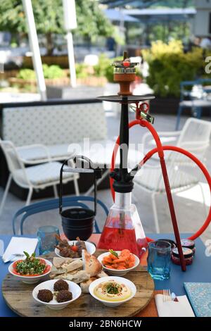 Hokah shisha sul tavolo del ristorante nel giardino. Gancio metallico su una terrazza estiva con sfondo sfocato. Foto Stock