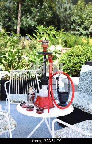 Hokah shisha sul tavolo del ristorante nel giardino. Gancio metallico su una terrazza estiva con sfondo sfocato. Foto Stock