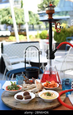 Hokah shisha sul tavolo del ristorante nel giardino. Gancio metallico su una terrazza estiva con sfondo sfocato. Foto Stock