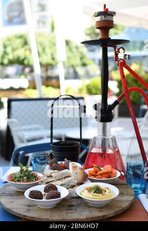 Hokah shisha sul tavolo del ristorante nel giardino. Gancio metallico su una terrazza estiva con sfondo sfocato. Foto Stock