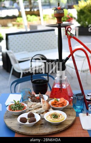 Hokah shisha sul tavolo del ristorante nel giardino. Gancio metallico su una terrazza estiva con sfondo sfocato. Foto Stock