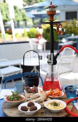 Hokah shisha sul tavolo del ristorante nel giardino. Gancio metallico su una terrazza estiva con sfondo sfocato. Foto Stock