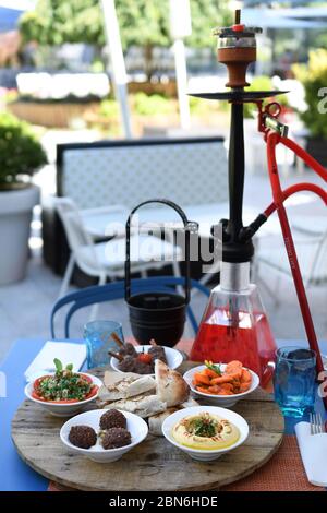 Hokah shisha sul tavolo del ristorante nel giardino. Gancio metallico su una terrazza estiva con sfondo sfocato. Foto Stock