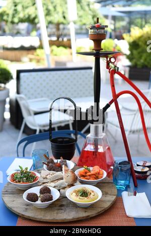 Hokah shisha sul tavolo del ristorante nel giardino. Gancio metallico su una terrazza estiva con sfondo sfocato. Foto Stock