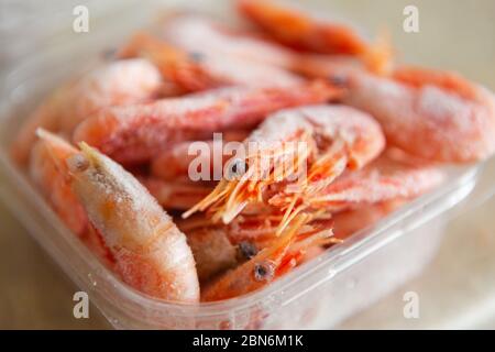 Gamberi surgelati in scatola contenitore di plastica su tavolo da cucina per cucinare.deliziosi gamberi in ghiaccio pronti per pasto preparation.Godetevi frutti di mare naturali con basso Foto Stock