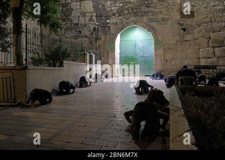 I fedeli musulmani effettuano la preghiera di Taraweeh davanti alle porte chiuse di Bab al-Asbat (la porta delle tribù) fuori della moschea di al-Aqsa durante il mese sacro musulmano di Ramadan nella Città Vecchia di Gerusalemme, in mezzo alla pandemia COVID-19 il 12 maggio 2020. La moschea al-Aqsa, situata sulla Piazza del Monte del Tempio a Gerusalemme, è stata chiusa 51 giorni fa dal Waqf, l'organismo religioso che gestisce i luoghi sacri musulmani nella Città Santa, una misura eccezionale volta a limitare la pandemia di Coronavirus. Foto Stock