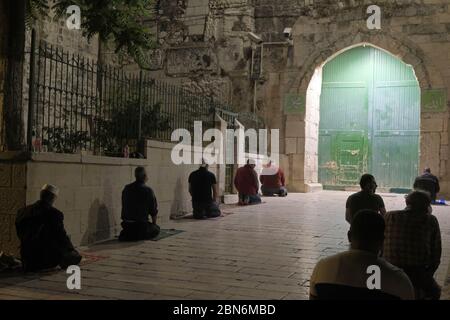 I fedeli musulmani effettuano la preghiera di Taraweeh davanti alle porte chiuse di Bab al-Asbat (la porta delle tribù) fuori della moschea di al-Aqsa durante il mese sacro musulmano di Ramadan nella Città Vecchia di Gerusalemme, in mezzo alla pandemia COVID-19 il 12 maggio 2020. La moschea al-Aqsa, situata sulla Piazza del Monte del Tempio a Gerusalemme, è stata chiusa 51 giorni fa dal Waqf, l'organismo religioso che gestisce i luoghi sacri musulmani nella Città Santa, una misura eccezionale volta a limitare la pandemia di Coronavirus. Foto Stock