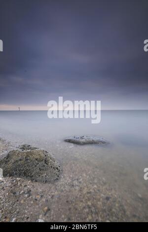 Pianure di sabbia con conchiglie e grandi massi a bassa marea. Il Mare di Wadden vicino a Moddergat, Paesens, Paesi Bassi. Patrimonio dell'umanità dell'UNESCO. Focu selettivo Foto Stock