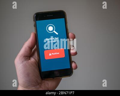 App mobile per covid-19. Test con risultati positivi per il coronavirus. La persona è un cellulare in mano. Foto Stock