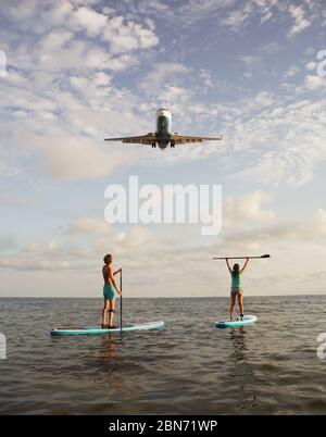 Giovane coppia che si accoppia a bordo del SUP con atterraggio aereo su sfondo Foto Stock