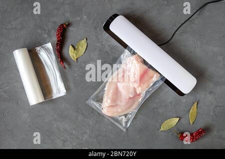 Filetto di tilapia in un sacchetto sottovuoto. Confezionamento sottovuoto di pesce. L'uso di un sigillante sottovuoto per lo stoccaggio a lungo termine dei prodotti. Vista dall'alto. Disposizione piatta. Foto Stock