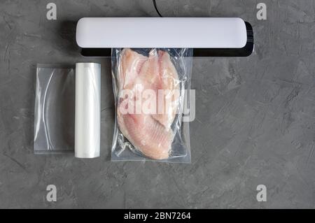 Confezionamento sottovuoto per pesci per conservazione a lungo termine. Filetto di tilapia in un sacchetto sottovuoto. Vista dall'alto. Disposizione piatta. Foto Stock