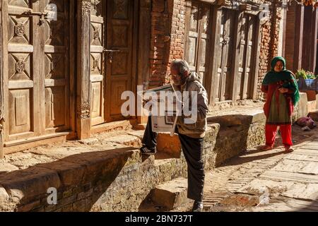 Dhulikhel, Nepal - 15 novembre 2016: Uomo nepalese che legge un giornale per strada. Foto Stock