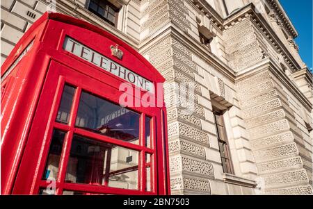 Una tradizionale vecchia scatola telefonica rossa del Regno Unito fuori da uno dei molti edifici governativi a Whitehall, Londra. Foto Stock