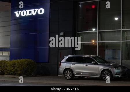 Volvo XC90 parcheggiato davanti a un concessionario Volvo nel centro di Toronto. Il logo di testo Volvo sull'edificio si illumina di notte. Foto Stock