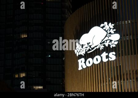 Roots Canada logo, una popolare società canadese di appello, visto in cima a un negozio nel centro di Toronto di notte. Foto Stock