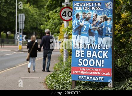 La gente cammina da un segno che dice 'ora non è il momento per gli hugs....ma saremo presto di nuovo!' Fuori dal McDiarmid Park, sede di St Johnstone. Foto Stock