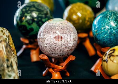 Pietra a forma di sfera con un segno come labbra sul supporto. Pietre varie gemme minerali. Sfondo naturale. Foto Stock