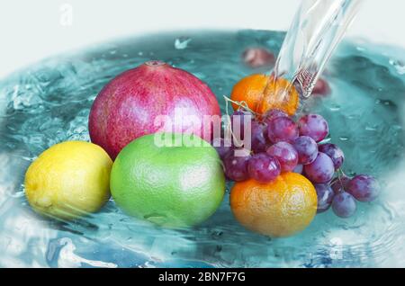 Frutta diversa nell'acqua sotto il getto di lavaggio Foto Stock