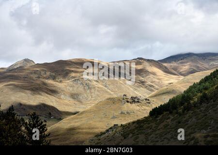 Caucaso, Georgia, regione Tusheti, Dartlo. Villaggio illuminato dal sole sulla cima di una montagna Foto Stock
