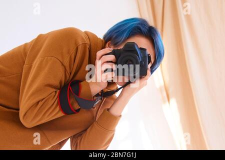 hipster ragazza che tiene la macchina fotografica e scatta la foto. closeup della mano della giovane donna con la macchina fotografica professionale in studio. concetto di giornata di fotografia del mondo Foto Stock