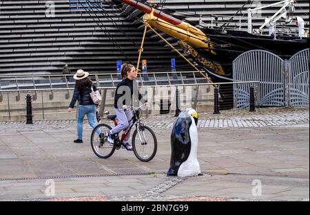 Dundee, Tayside, Scozia, Regno Unito. 13 maggio 2020. Tempo: Nuvoloso con alcuni intervalli soleggiati attraverso Tayside in Scozia con temperatura massima 14°C. Il primo Ministro Nicola Sturgeon ha annunciato nuove indicazioni che raccomandano al popolo scozzese di rendere obbligatorio indossare maschere in pubblico. Nonostante le normative sulla maschera facciale, i residenti locali si allenano alla luce lungo il lungomare di Dundee. Una giovane ciclista femminile ha una giornata fuori in bicicletta la sua bicicletta Olympus lungo Discovery Point accanto al V&A Design Museum e la nave RRS Discovery. Credit: Dundee Photographics/Alamy Live News Foto Stock