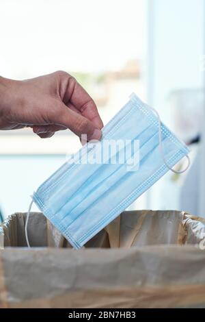 primo piano di un uomo che lancia una maschera chirurgica al cestino può Foto Stock