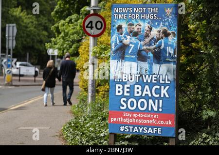 La gente cammina da un segno che dice 'ora non è il momento per gli hugs....ma saremo presto di nuovo!' Fuori dal McDiarmid Park, sede di St Johnstone. Foto Stock