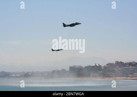 Serie 111 di 165 due McDonnell Douglas AV-8B Harrier II passaggio al volo in piano con la spiaggia e gli edifici dietro Al giorno delle forze armate in Spagna Foto Stock