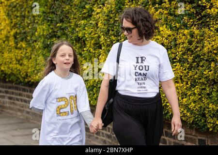 Fiona e sua figlia Lola, di Londra, indossano le T-shirt che includono lo slogan: "Se potete leggere questo, siete troppo vicini per COVID" che sono stati lanciati dalla società globale di trasformazione del marchio FutureBrand come un'iniziativa no-profit per contribuire a rafforzare le linee guida chiave di distanza sociale come la nazione emerge dal blocco pandemico del coronavirus. Foto Stock