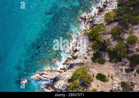 vista aerea dall'alto di un oceano limpido con splendide onde marine che si infrangono sulla costa rocciosa dell'isola con spray e schiuma, concetto di stile di vita avventuroso e s. Foto Stock