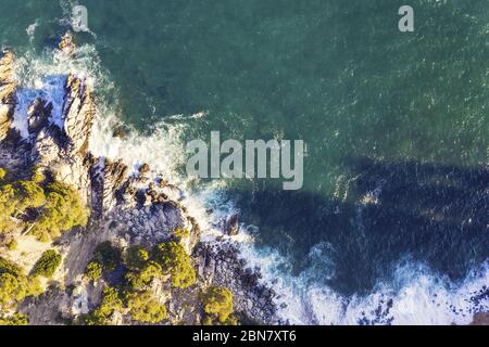 vista aerea dall'alto dell'oceano splendide onde marine che si infrangono sulla costa rocciosa dell'isola con spray e schiuma, concetto di stile di vita avventuroso e vacanza estiva Foto Stock