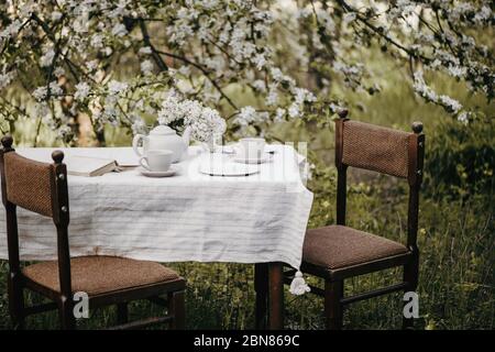 Tavolo da pranzo con tisane e tisane nel bellissimo giardino fiorito. Foto Stock