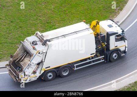 Grande camion per il trasporto di rifiuti domestici viaggia lungo l'autostrada della città, vista aerea Foto Stock