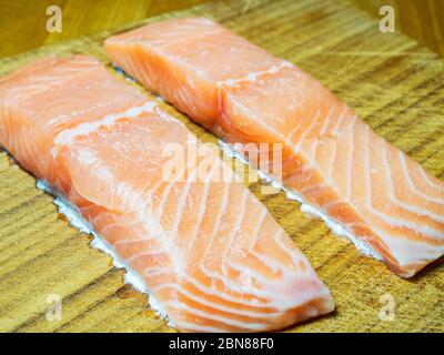 Due filetti di salmone crudo su un tagliere di legno Foto Stock