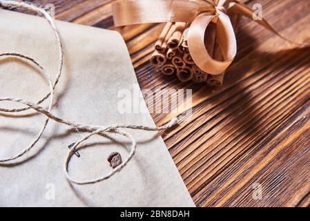 bastoncini di cannella legati con nastro marrone su sfondo di legno Foto Stock