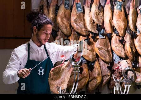 Il lavoratore maschile del negozio affetta abilmente prosciutto iberico a Viandas, Leadenhall Market, Londra, Regno Unito Foto Stock