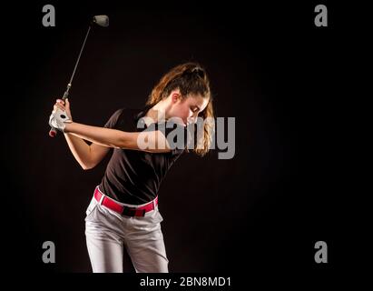 Ragazza alla ricerca del golf perfetto colpo isolato su sfondo nero Foto Stock