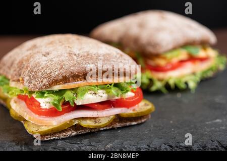 Due panini con salsiccia, formaggio e verdure su un vassoio. Sandwich a base di grano saraceno. Foto Stock