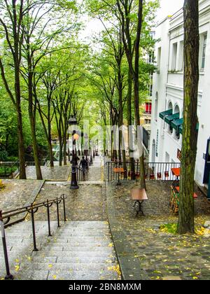 Gradini alberati che conducono in discesa a Montmartre, Parigi, durante una mattina piovosa prima dell'arrivo dei turisti Foto Stock