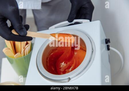 Come fare la ceretta. Fai da te donne. Fase 4 di 8 attendere che la cera si riscaldi e raccoglierla con una spatola. Foto Stock