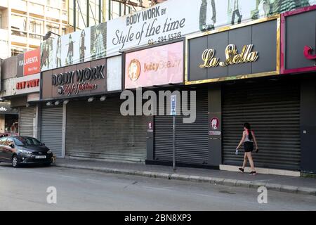 Beirut, Libano. 13 maggio 2020. Una donna cammina oltre negozi chiusi a Beirut, Libano, il 13 maggio 2020. Il numero di infezioni da COVID-19 in Libano è aumentato mercoledì di otto casi a 878, mentre il numero di decessi è rimasto invariato a 26, la National News Agency ha riferito. Il Libano chiude l'intero paese da mercoledì per i prossimi quattro giorni nel tentativo di limitare la diffusione del virus dopo aver assistito a un aumento delle infezioni negli ultimi giorni. Credit: Bilal Jawich/Xinhua/Alamy Live News Foto Stock