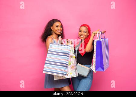 due belle giovani donne africane in posa con borse per la spesa, sentendosi eccitate Foto Stock