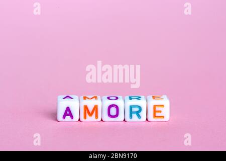 La parola amore in italiano. Beads sotto forma di cubo con testo su sfondo rosa. Progettazione concettuale. Buon San Valentino Foto Stock